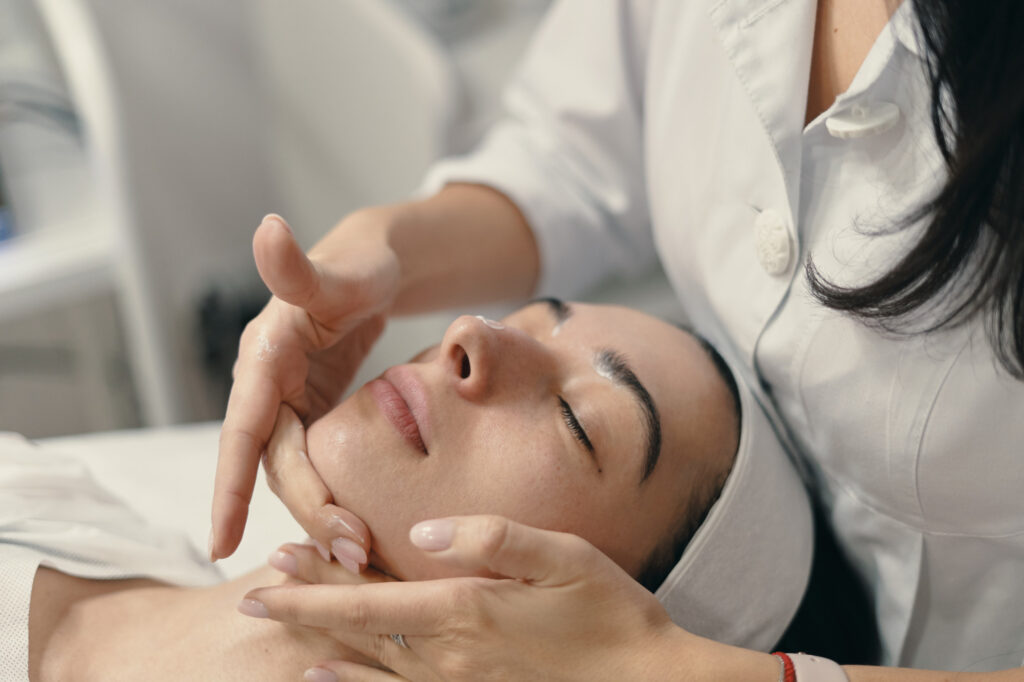 Hands of specialist doing facial treatment on face of a client