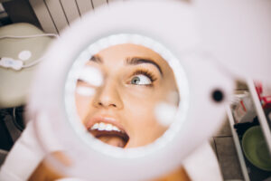 Woman's reflection on a mirror after treatment of dermal fillers around eyes